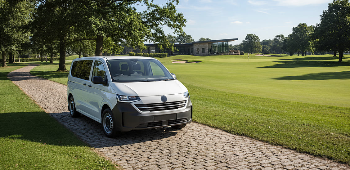 Furgoneta de pasajeros blanca Volkswagen circulando por un camino empedrado en las inmediaciones de un campo de golf.